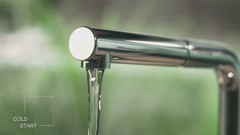 A running water tap with light reflections on the metal and a blurred background. 