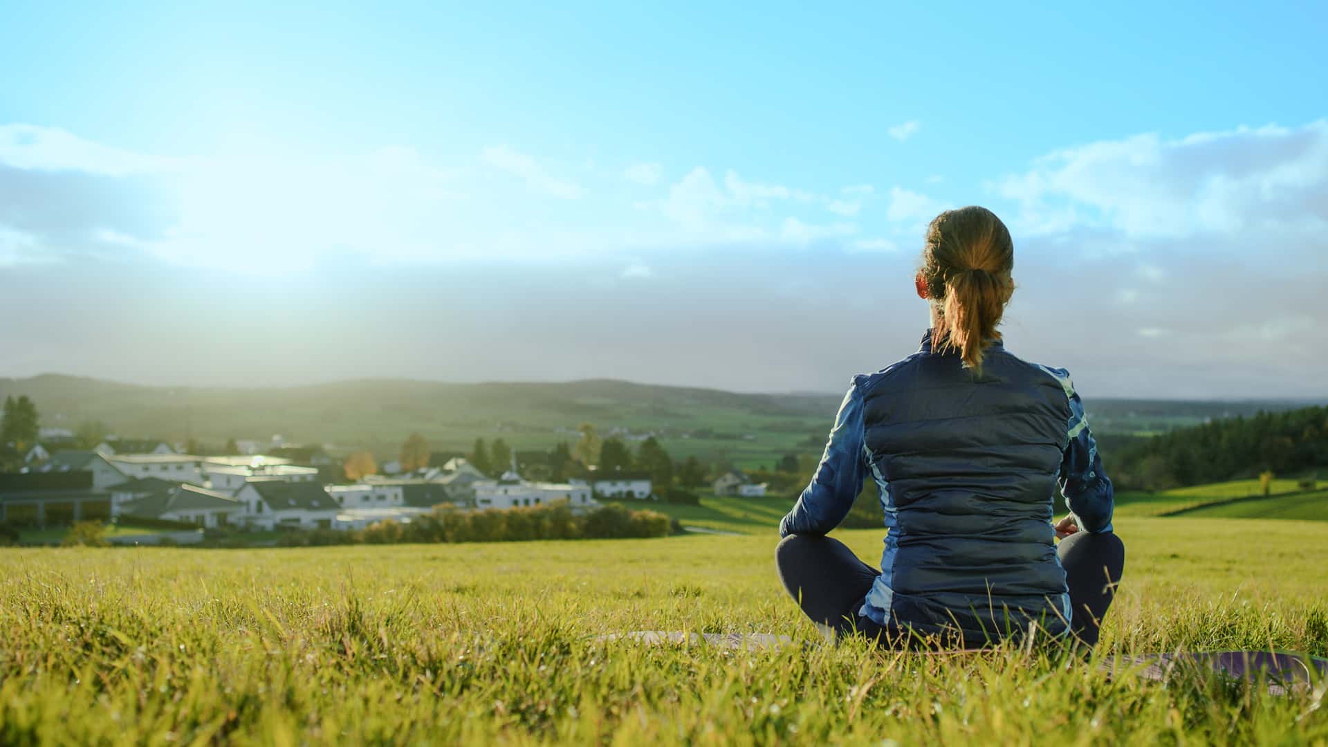Imagefilm Standbild für die Marke F&S concept Projektentwickler, das eine Best Ager Frau beim Meditieren in der Natur auf einer Wiese zeigt