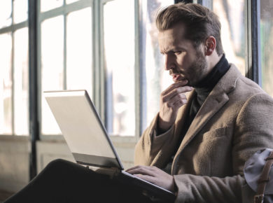 Man with Coat thinking about a Grey Laptop