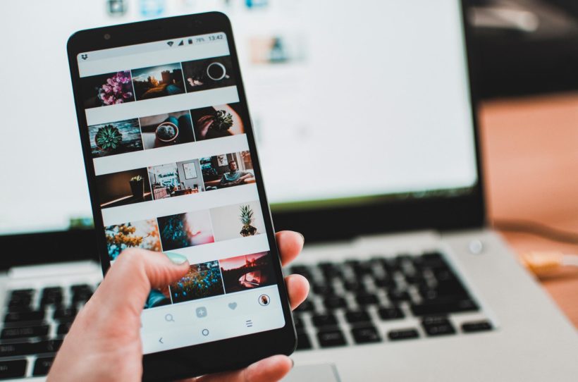 Smartphone mit Instagram Feed vor Laptop